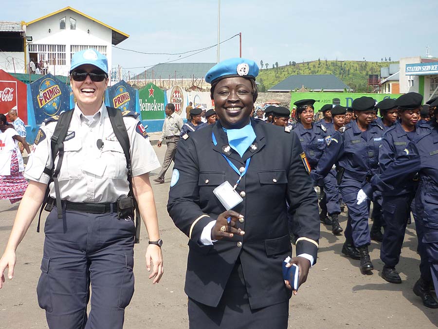 La s.é.-m. Jane Boissonneault (g.) et une consœur tchadienne de la police des Nations Unies sourient au défilé de la Journée internationale des femmes à Goma (RDC), en 2011.