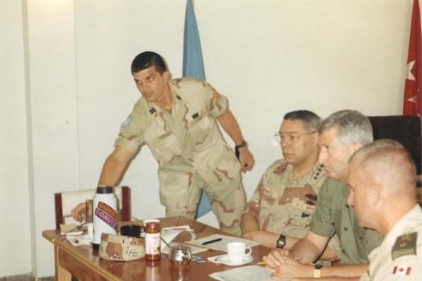 Visite du Général Colin Powell, au QG militaire de l’UNSOM II, Mogadiscio, 4 avril 1993. Debout (de gauche à droite) l’officier d’état-major de l’armée américaine, le général Powell, le général de corps d’armée turc Cevik Bir, commandant de la force de l’ONUSOM II, le général de division de l’armée canadienne Jim Cox, chef d’état-major de la force de l’ONUSOM II.