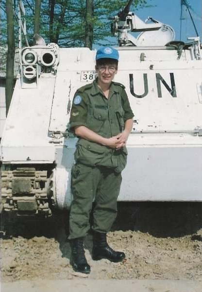 Devant un véhicule blindé de transport de troupes canadiennes portant les marques des Nations Unies.