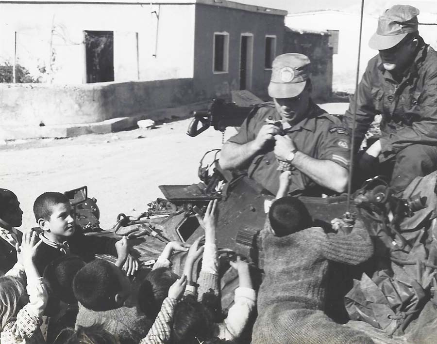 L'une des principales missions de l'escadron est la « patrouille à longue distance ». Une troupe canadienne de voitures d'éclaireurs effectuait des tâches de reconnaissance et visitait des villages et des hameaux éloignés pour s'assurer de la sûreté, de la santé et de la sécurité des résidents. Cette photo montre le Cpl Rudy Jodoin partageant des friandises avec les enfants du village.