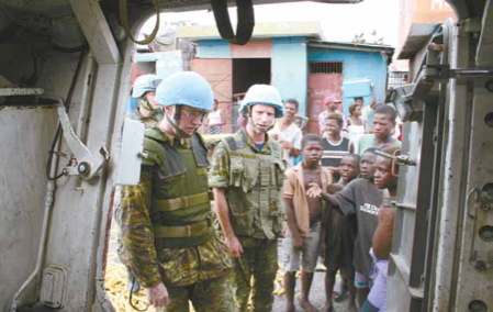 Le Col (ret.) Thomas Tarrant et le Maj Mark Sullivan inspectent un transport de troupes blindé pendant une patrouille dans Cité Soleil. PHOTOS : MINUSTAH MILITARY PAO/OAP DE LA MINUSTAH